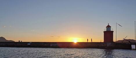 A lighthouse at sunset with a clear sky and calm water.