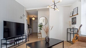 Ein modernes Wohnzimmer mit Flachbildfernseher, Couch, Couchtisch und einer Gitarre.