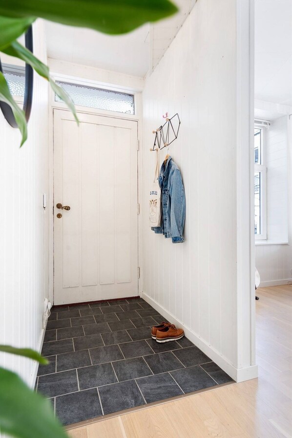 A hallway with a white door, a black tiled entrance mat, and a pair of shoes on the floor. - Cozy 1-bedroom Apartment in Ålesund's Heart (Ålesund)
