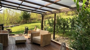 A wooden deck with outdoor furniture, a pergola, and a view of a garden. - Au moulin - GEX - Gîte (GEX)