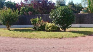 A paved driveway leading to a grassy area with a stone wall and various shrubs. - Gîte "la belle étoile" 2 persons (Le Fenouiller)