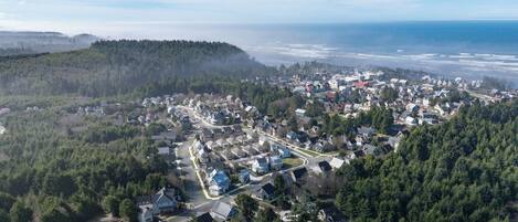 Vue aérienne d’un quartier résidentiel avec des maisons, des routes et une colline boisée.