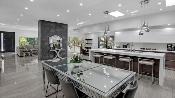 A modern kitchen with a central island, bar stools, and pendant lighting.