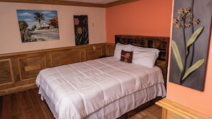 Une chambre à coucher avec une tête de lit en bois, un couvre-lit blanc et deux tableaux encadrés accrochés au mur.