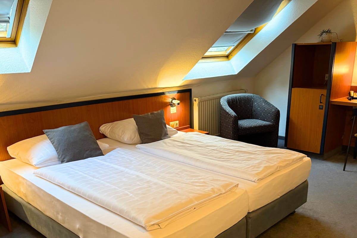 A double bed with a headboard, two pillows, and a bedside table with a lamp.