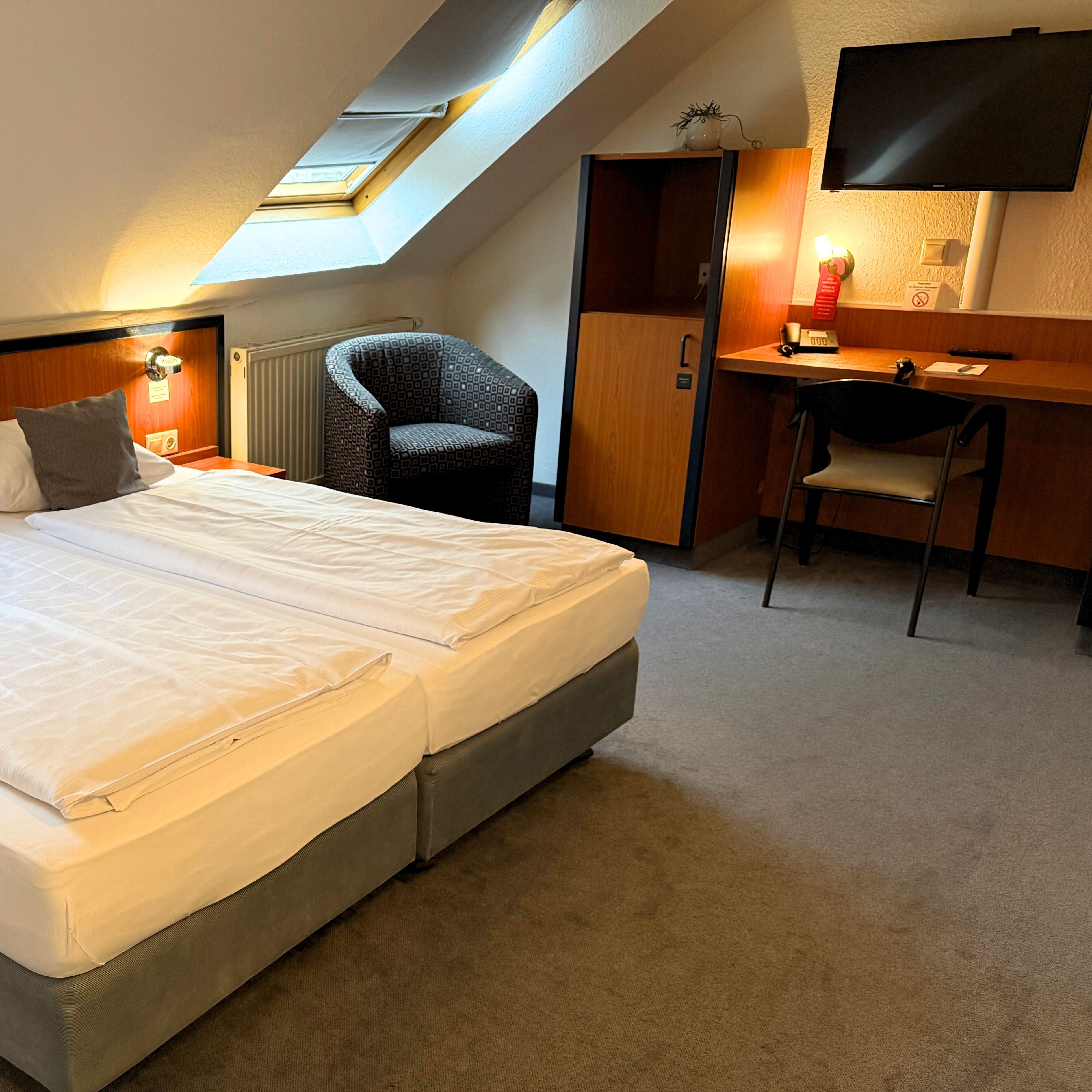 Une chambre d’hôtel équipée d’un lit, d’un bureau, d’une chaise, d’une armoire et d’un téléviseur.