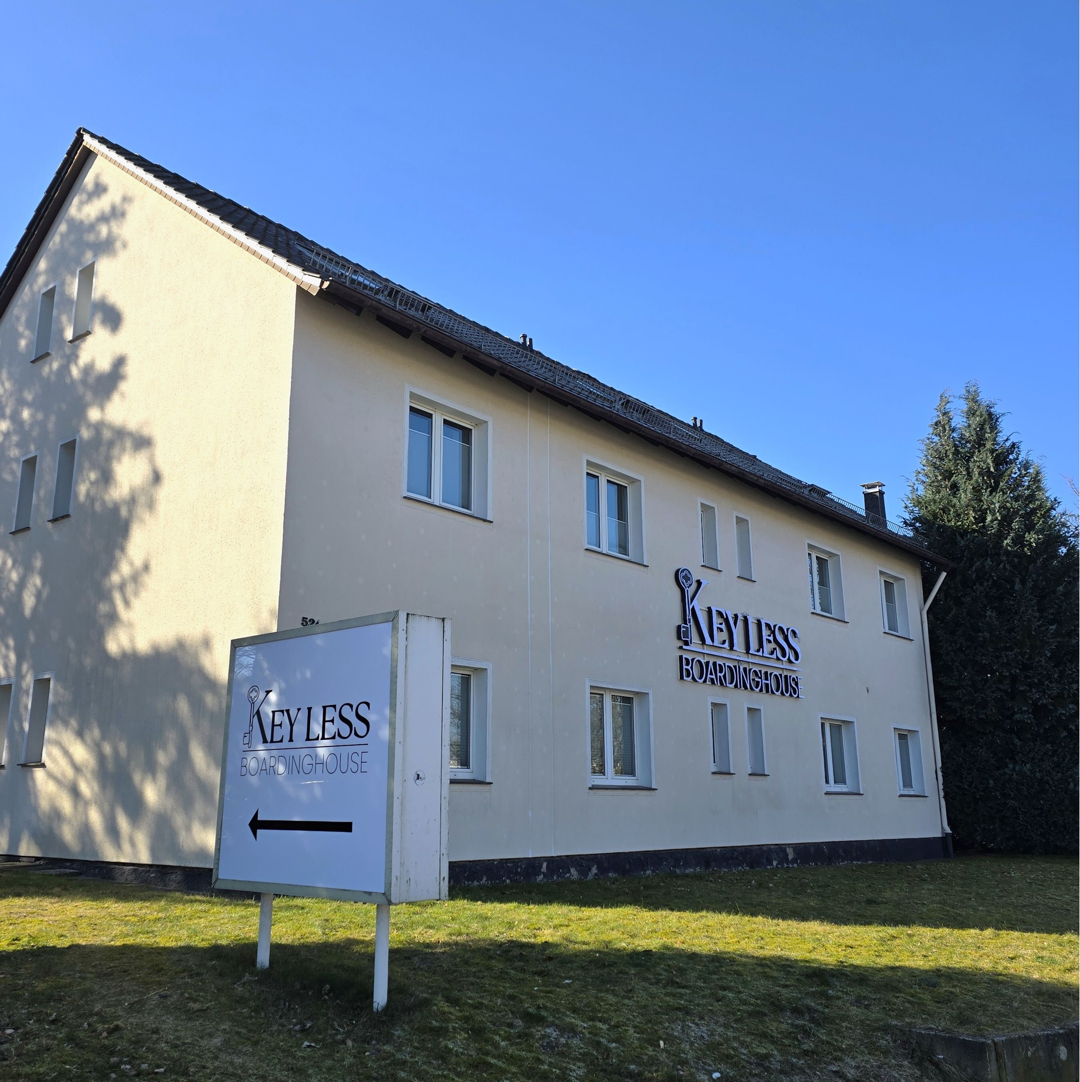 A building with a sign reading "Keyless Boardinghouse" and a directional arrow sign.