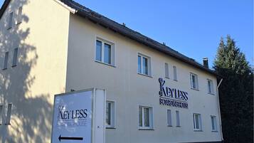 A building with a sign reading "Keyless Boardinghouse" and a directional arrow sign.