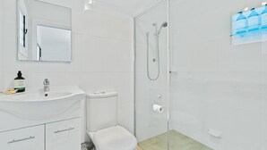 Ein modernes Badezimmer mit Waschbecken, Spiegel und Toilette in Weiß.