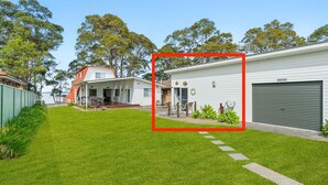 Ein Wohnhaus mit gepflegtem Rasen, einer überdachten Außenlounge und einer Garage.