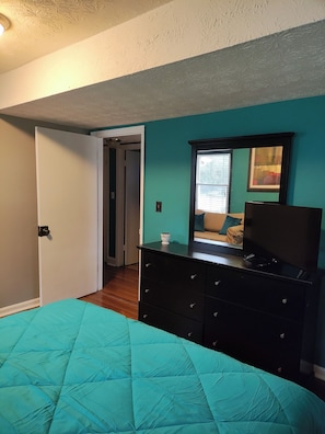 Cozy retreat with a comfortable bed, dresser, and mirror.