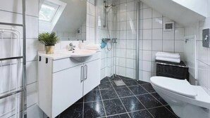 Une salle de bain moderne avec un puits de lumière, des carreaux blancs, un sol en marbre noir, un lavabo, des toilettes et une douche.