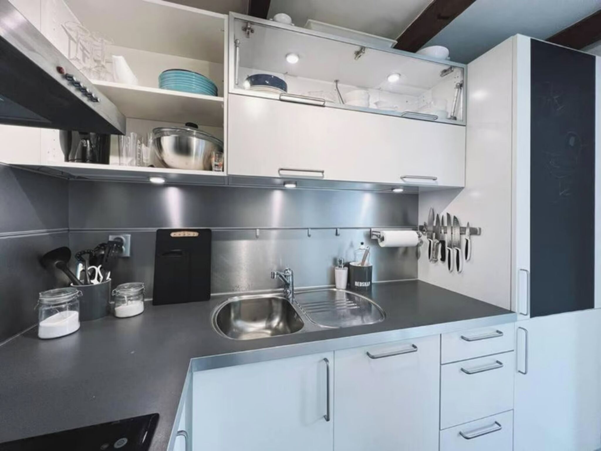 A modern kitchen with stainless steel appliances, a double sink, and overhead cabinets.