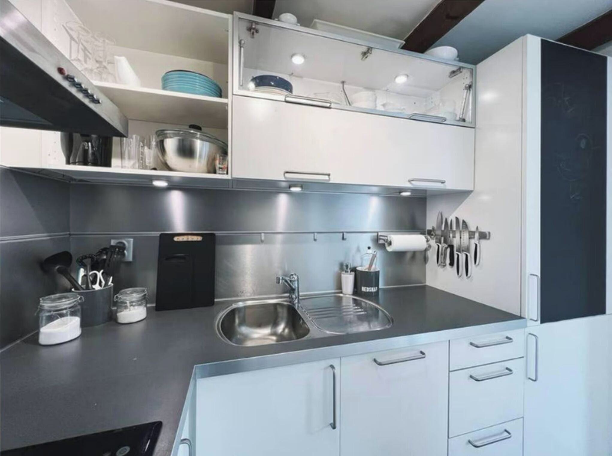 Een moderne keuken met roestvrijstalen apparatuur, witte keukenkastjes en een ingebouwd spoelbak.