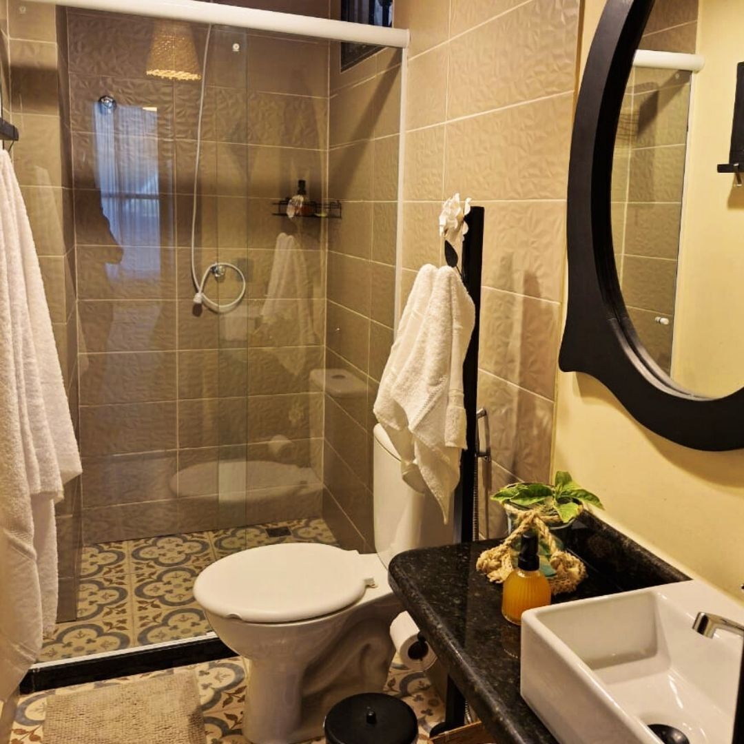 Un baño con ducha de vidrio, inodoro, lavamanos y espejo.