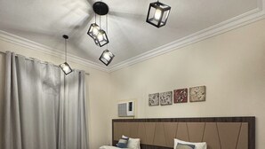 Una habitación de hotel con dos camas, un ventilador de techo y una mesita de noche con lámpara.