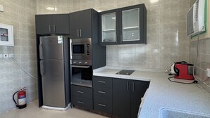 Una cocina moderna con armarios oscuros, un refrigerador de acero inoxidable, un microondas y un lavamanos.