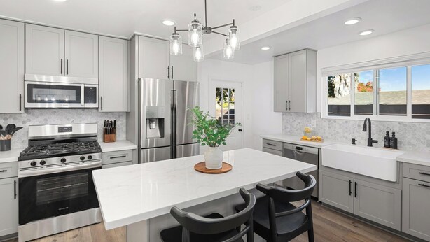 Una cocina moderna con electrodomésticos de acero inoxidable, encimera de mármol blanco y una isla grande con taburetes de bar.