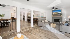 Una sala de estar moderna con chimenea, un comedor y una cocina al fondo.