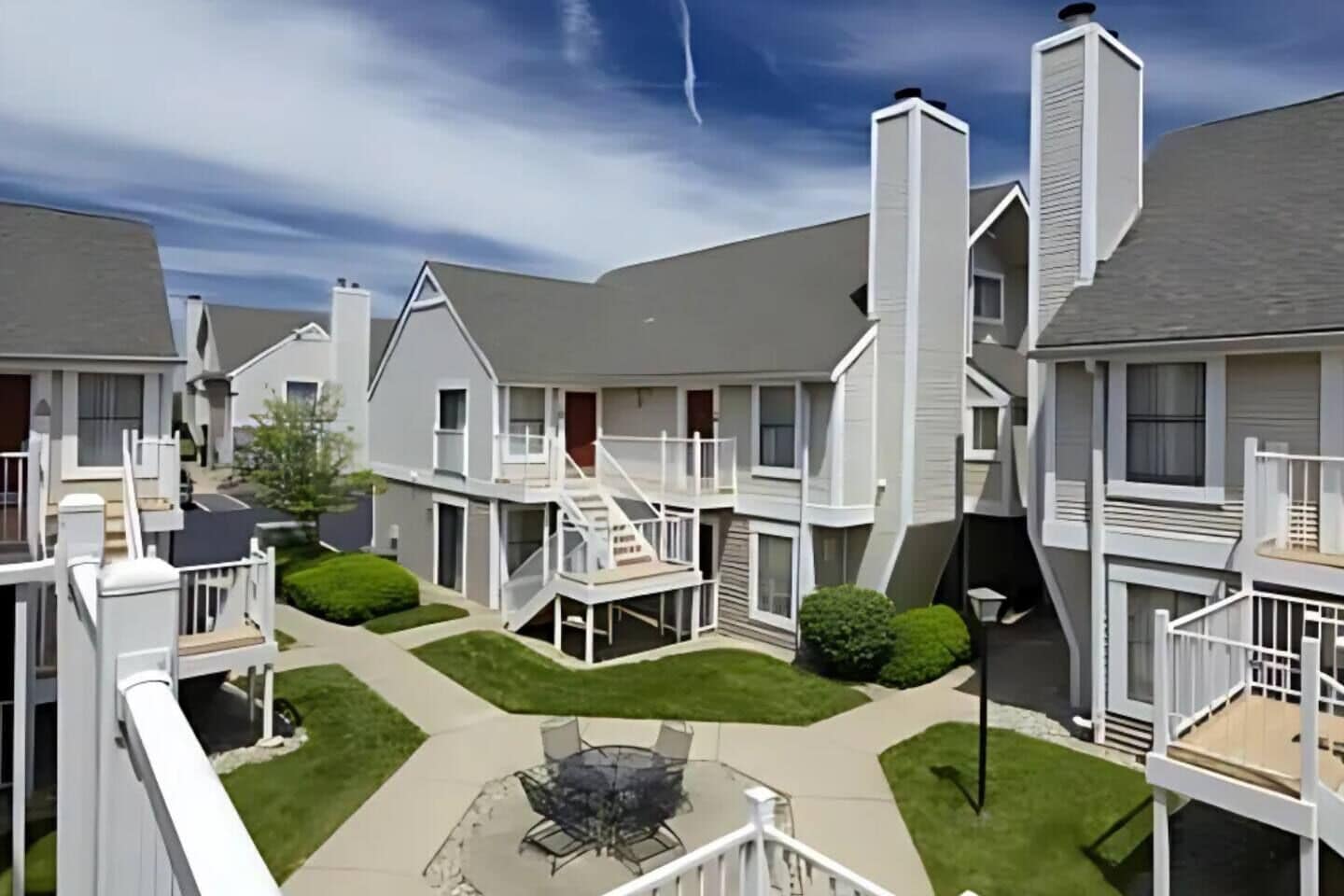 A courtyard with a central patio, surrounded by multi-story buildings with balconies and staircases.