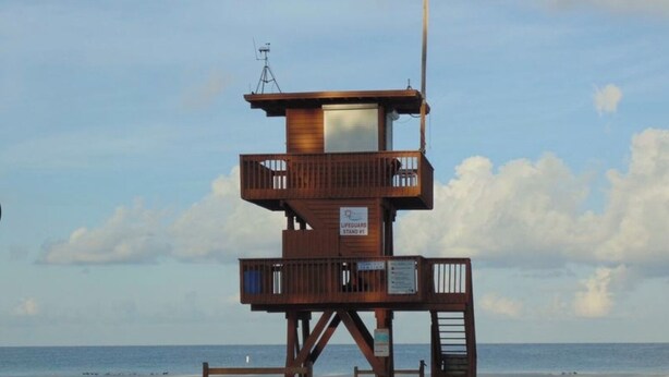 A lifeguard tower with a wooden structure, a metal antenna, and a sign indicating it is a lifeguard station. - Cozy Cottage, 1 bedroom sleeps 2 (Bradenton Beach)