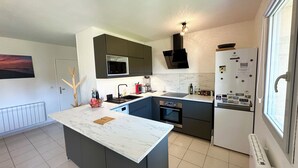 Een moderne keuken met een centraal eiland, donkere kastjes, een magnetron, een fornuis en een koelkast.