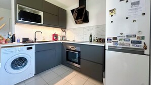 Een moderne keuken met een ingebouwde wasmachine, een magnetron, een broodrooster en een koelkast.
