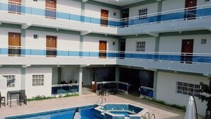 Ένα πολυώροφο ξενοδοχείο με πισίνα, εξωτερικό χώρο για καθιστικό και μπαλκόνια.