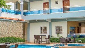 Ένα πολυώροφο ξενοδοχείο με χώρο πισίνας, εξωτερικό χώρο για καθιστικό και θέα στο γύρω τοπίο.
