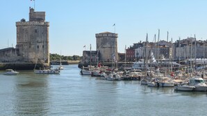 A harbor with multiple boats docked, a large stone tower, and a smaller tower with a flag. - Cozy apartment in La Rochelle with WiFi (La Rochelle)