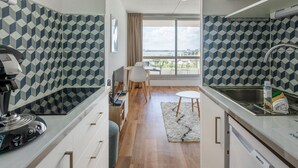 A modern kitchen with a built-in stove, a sink, and a window with a view of the city. - Cozy apartment in La Rochelle with WiFi (La Rochelle)
