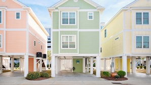 A row of three-story townhouses with a covered entrance and a small garden area in front. - Charming 4-bedroom Myrtle Beach Home ~ Ocean View, Wi-Fi, Pool, & More! (Myrtle Beach)