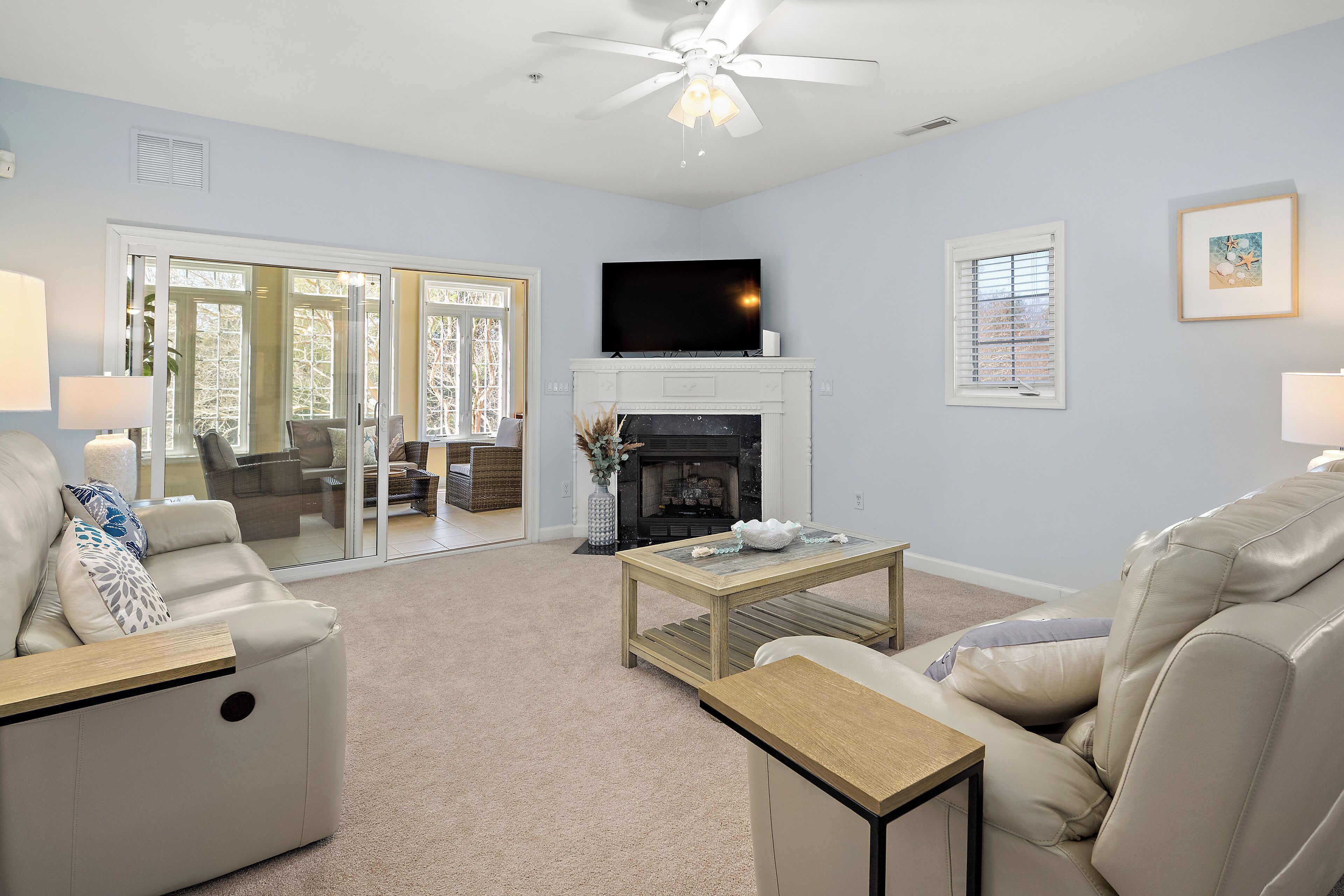 A living room with a fireplace, a television, and a ceiling fan.