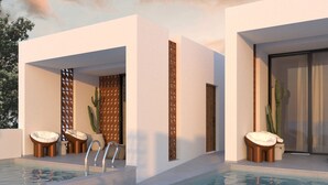 Un área de piscina moderna con sillones de descanso y un bar junto a la piscina.
