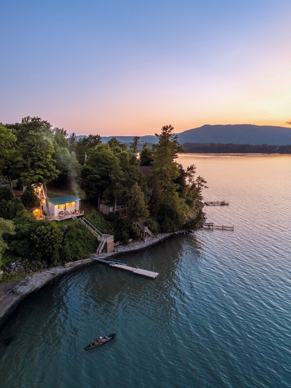 A lakeside property with a dock, a small house with a deck, and a boat.
