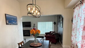 Ein Essbereich mit einem Holztisch und Stühlen, einer Vase mit Blumen sowie einem modernen Kronleuchter.