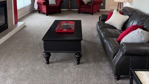 Ein Wohnzimmer mit Kamin, zwei roten Sofas, einem schwarzen Ledersessel und einem Couchtisch.
