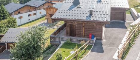 A cluster of wooden cabins with metal roofs, surrounded by lush greenery and hills.