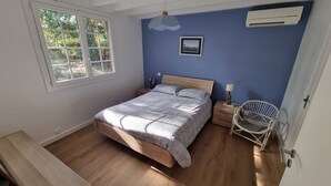 A bedroom with a bed, bedside tables, a chair, a window, and an air conditioning unit. - CAPBRETON. Villa ALAMEAT with garden for 6 people. Free Wifi. (CAPBRETON)