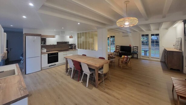 A modern kitchen with white cabinets, a wooden dining table, and a large window. - CAPBRETON. Villa ALAMEAT with garden for 6 people. Free Wifi. (CAPBRETON)