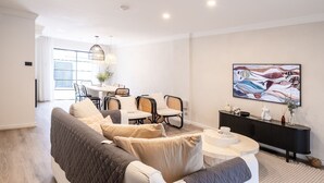 A modern living room with a sofa, dining table, chairs, and a large abstract painting.