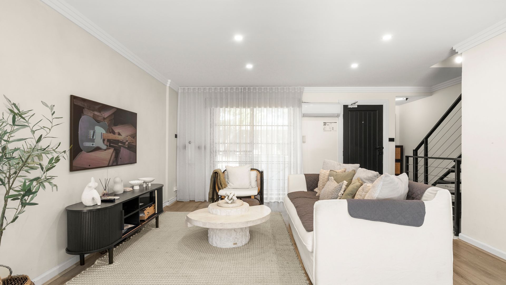 A modern living room with a sofa, a round coffee table, and a painting on the wall.
