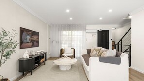 Un salon moderne avec un canapé, une table basse ronde et un tableau accroché au mur.