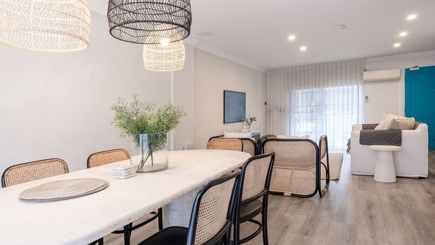 A modern dining area with a white table, wicker chairs, and a vase with greenery. - The Euston Social in Alexandria (Alexandria)
