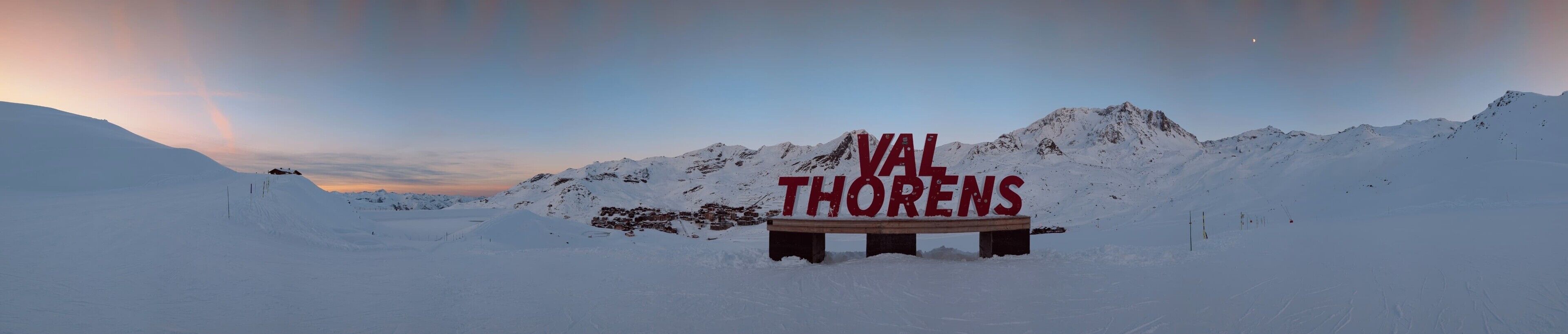 Paesaggio innevato con un cartello che riporta la scritta 'VAL THORENS' in primo piano.