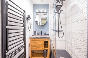 A bathroom with a vanity, mirror, towel rack, and shower. - Apartment '6 Couchages Val Thorens' with Mountain View, Balcony and Wi-Fi (Val Thorens)