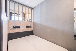 A single bed with a wooden headboard, a small shelf with a lamp, and a mirror above the bed. - Apartment '6 Couchages Val Thorens' with Mountain View, Balcony and Wi-Fi (Val Thorens)