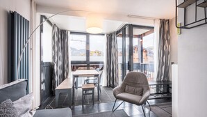 A modern room with a sofa, a chair, a table, and a view through large windows. - Apartment '6 Couchages Val Thorens' with Mountain View, Balcony and Wi-Fi (Val Thorens)