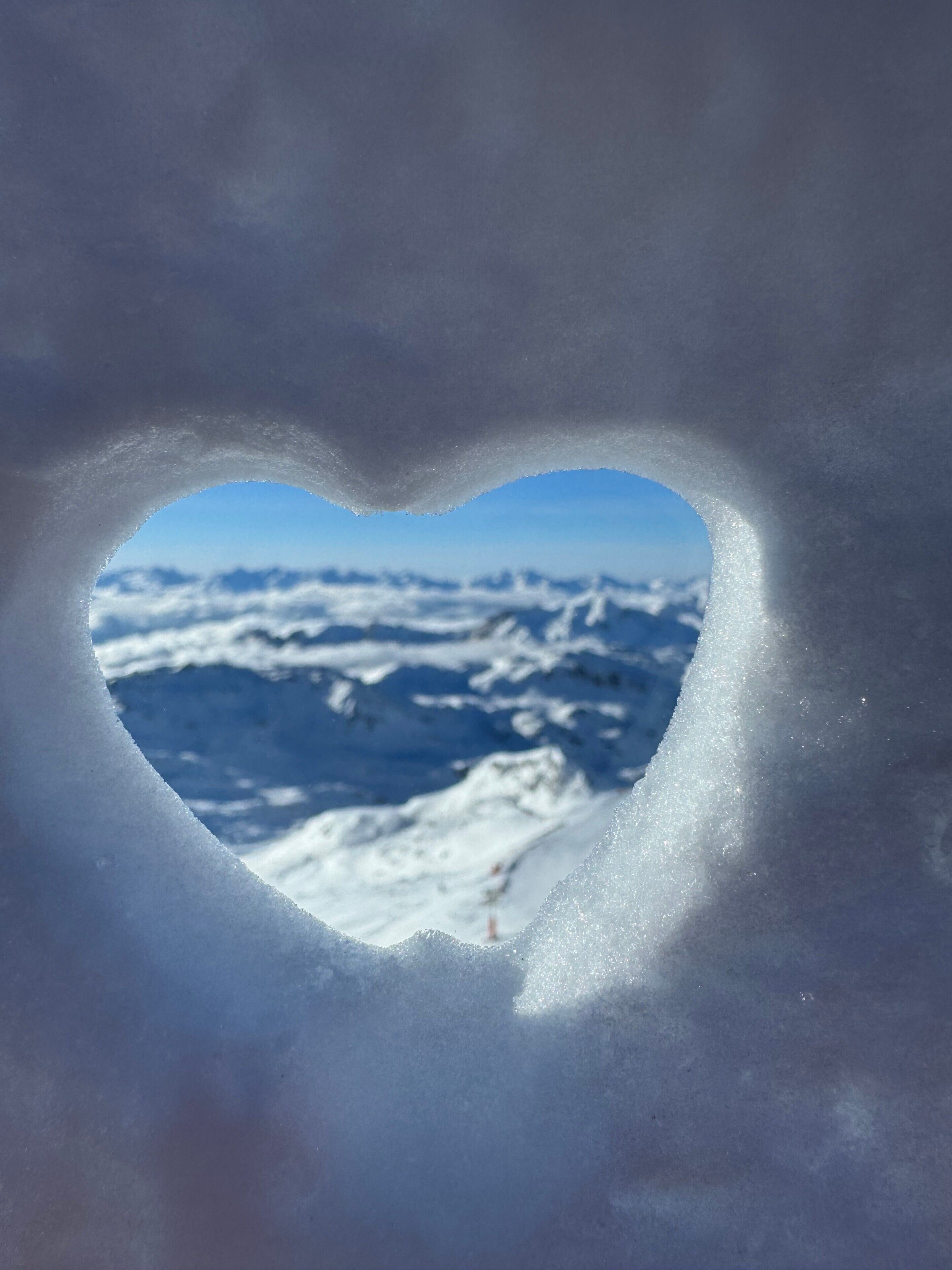 A heart-shaped window with a snowy mountain view.
