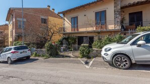 A residential street with houses, a white car parked on the side, and a gated entrance.